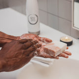 Person washing hands with coconut oil soap vegan soap in a bathroom setting